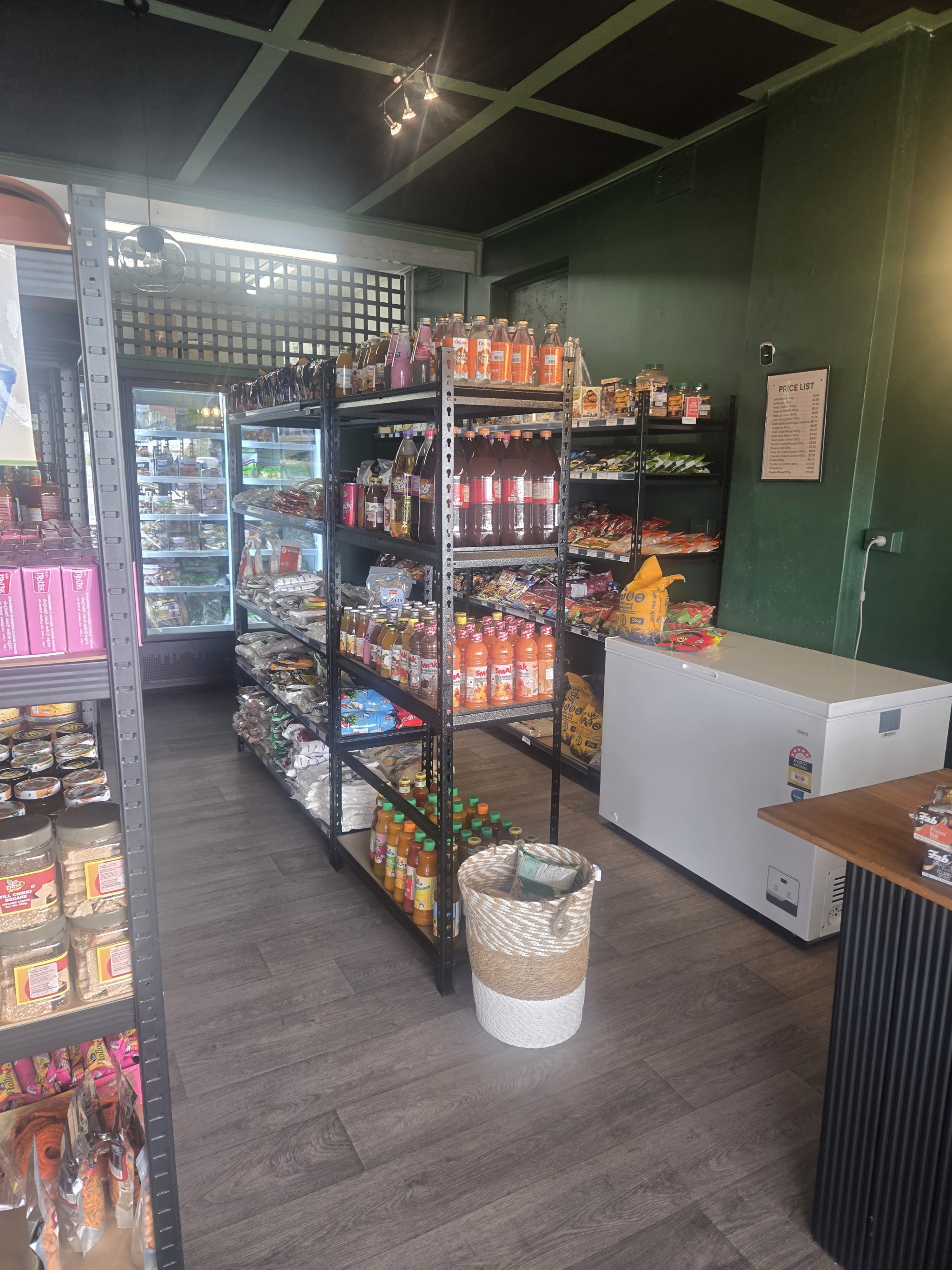 Inside the Tropical Mart: shelves of drinks and snacks, green walls and a chest freezer