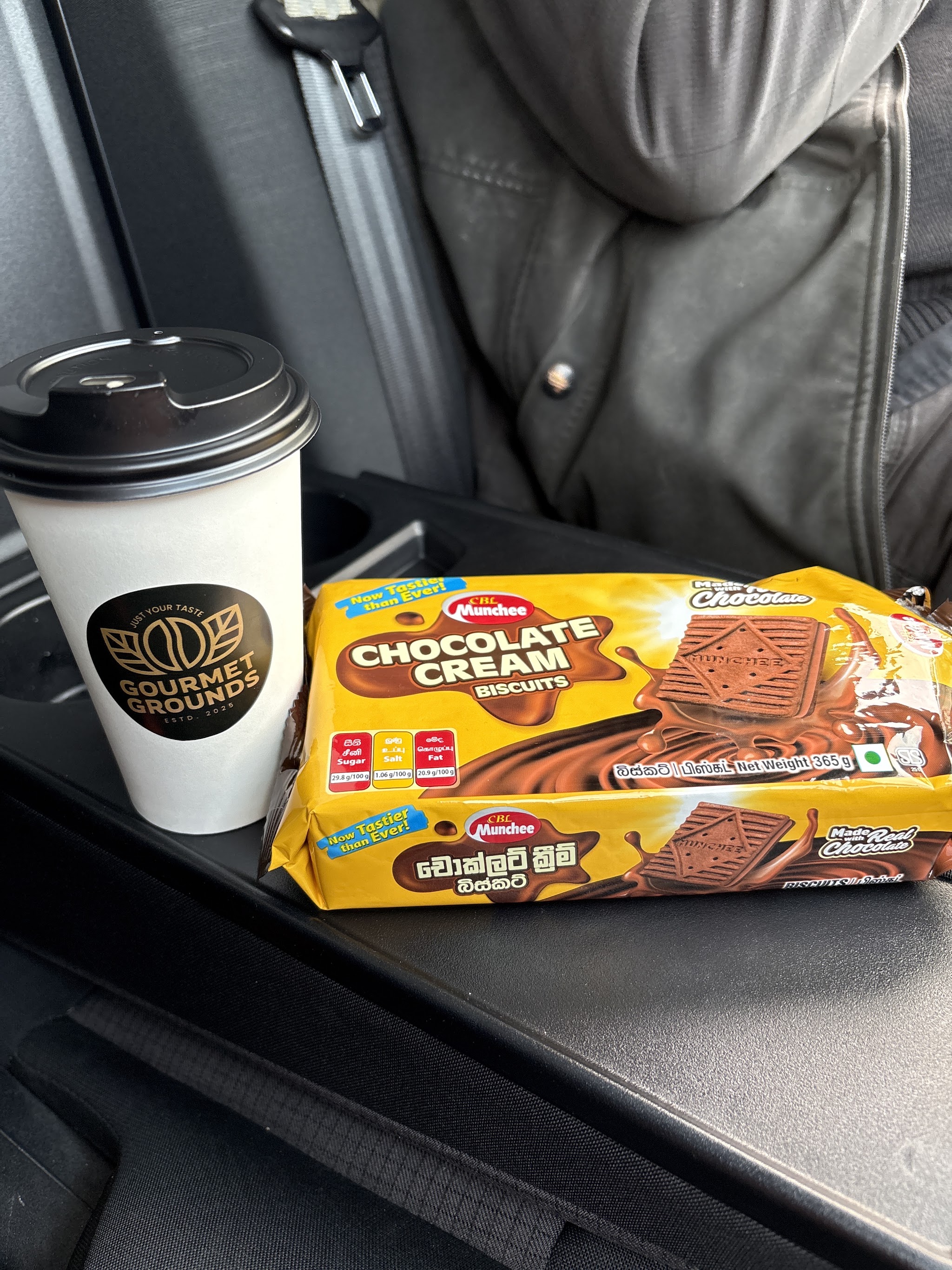 A Gourmet Grounds coffee cup next to a pack of Munchee Chocolate Cream biscuits