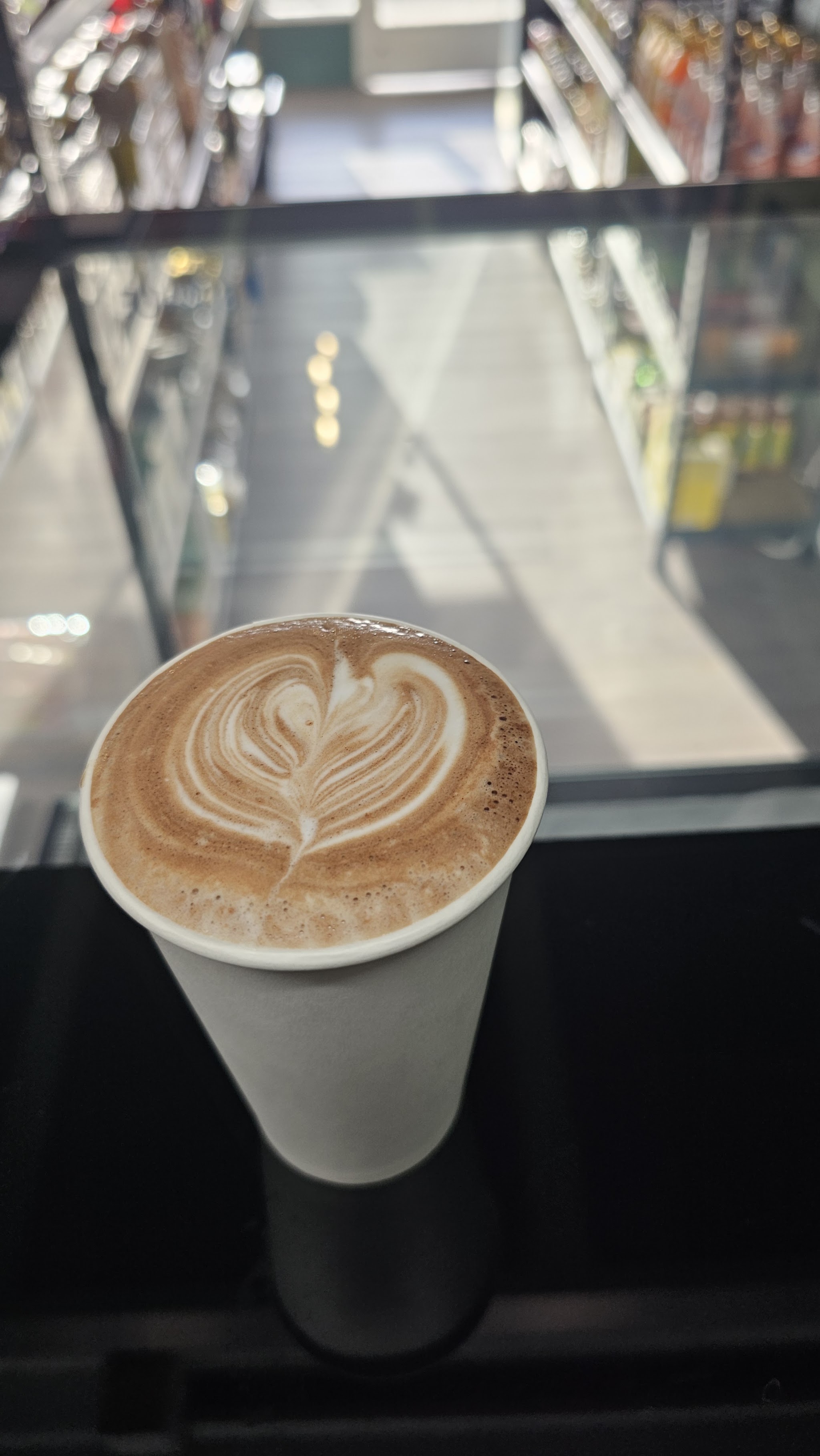 Takeaway coffee with heart latte art on the glass counter